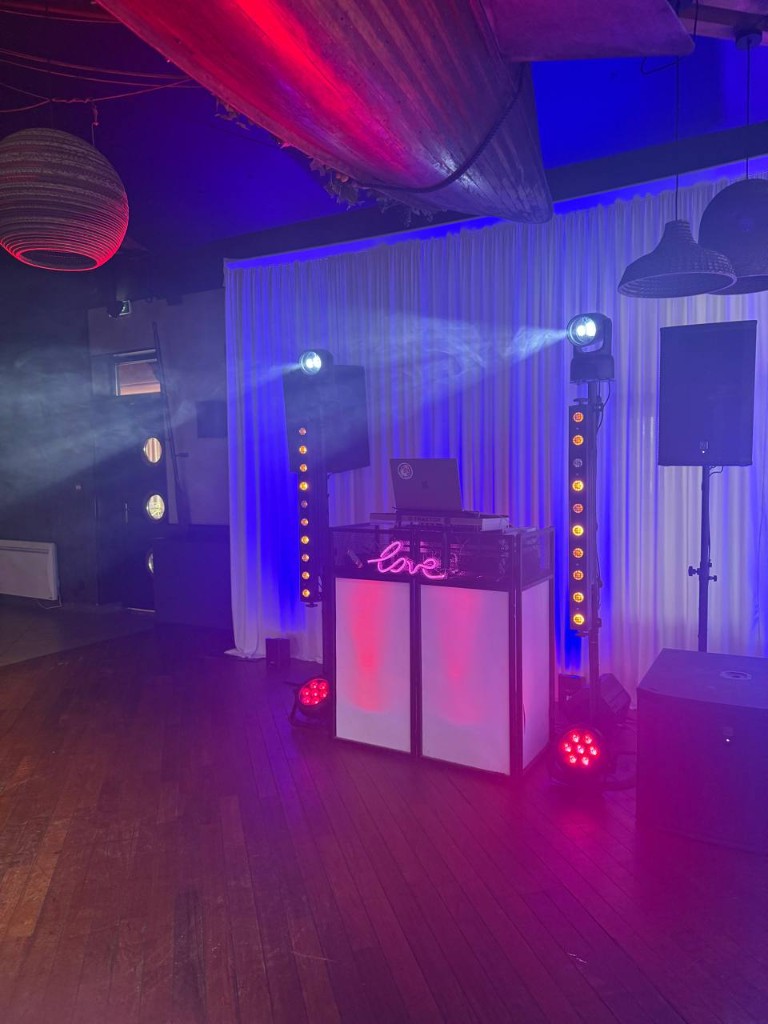 Stand DJ devant un rideau blanc, parquet et lumières bleues et rouges