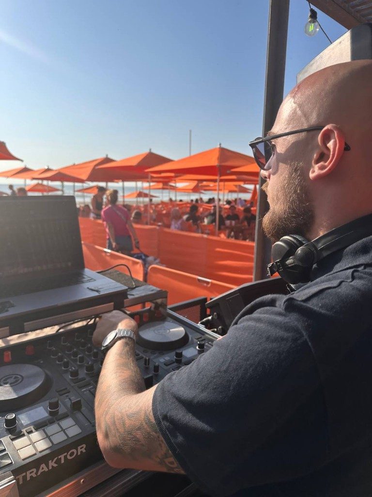 Simba Léone aux platines face à la mer, parasols orange