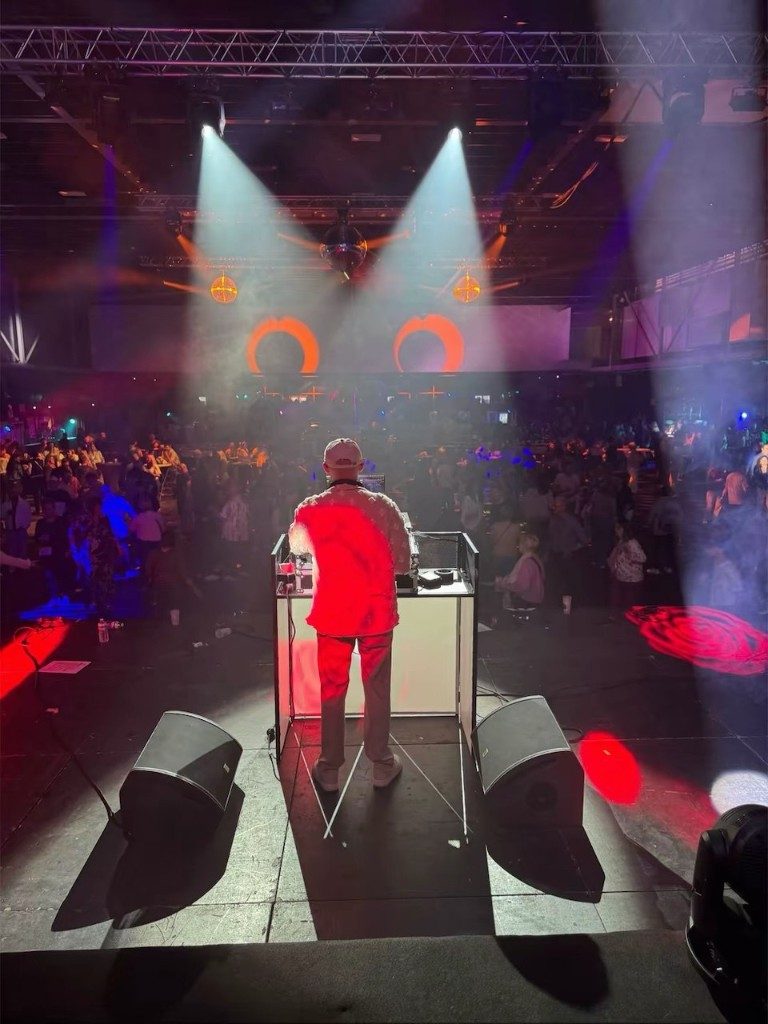 Simba Léone de dos face à une salle pleine, faisceaux de lumière et boule à facettes